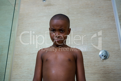 Low angle portrait of shirtless boy standing against wall
