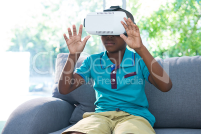 Boy wearing virtual reality headset with arms raised at home