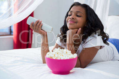 Girl with hand on chin watching television at home
