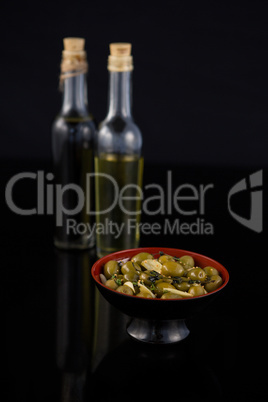 Close-up of marinated olives with olive oil and balsamic vinegar bottle