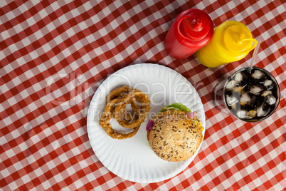 Hamburger, french fries, onion ring and cold drink on napkin