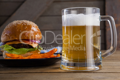 Burger and french fries in plate with glass of beer
