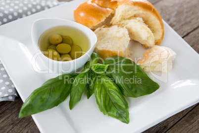 Pickled olives with herbs and bread in platter