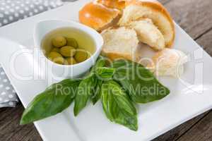 Pickled olives with herbs and bread in platter