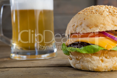 Burger with glass of beer on wooden table