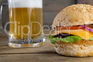Burger with glass of beer on wooden table
