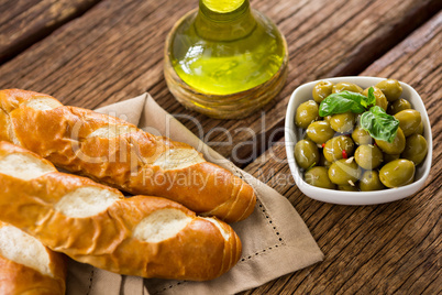 Marinated olives with olive oil and breakfast on wooden table