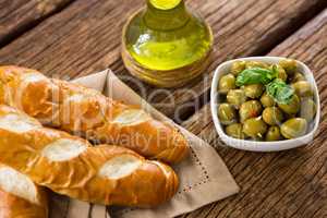 Marinated olives with olive oil and breakfast on wooden table