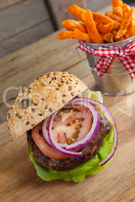 Hamburger and french fries on chopping board