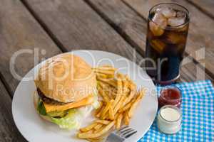 High angle view of cheeseburger and french fries by dip with drink
