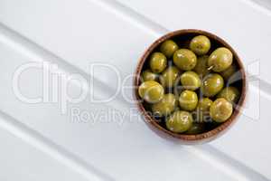 Marinated green olives in a wooden bowl on table