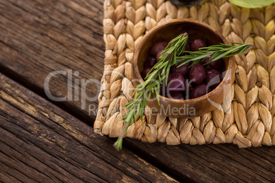 Marinated olives in bowl and rosemary herb on bamboo mat