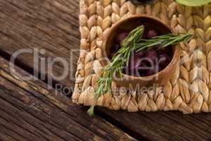 Marinated olives in bowl and rosemary herb on bamboo mat