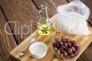 Marinated olives, oil bottle and salt on chopping board