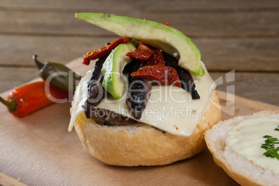 Chili peppers and burger on chopping board