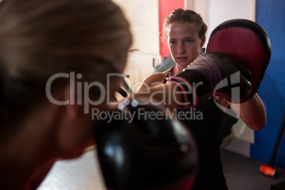 Female boxer punching mitts with instructor