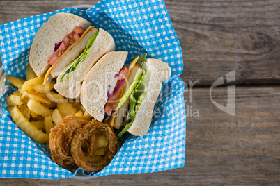 Overhead view of sliced burger with French fries and onion rings