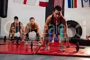 Portrait of female athlete lifting barbell with friends