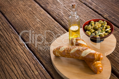 Marinated olives, bread and olive oil on heart shape board