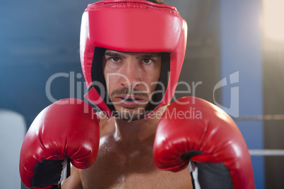 Close-up portrait of confident male boxer wearing red headgear and gloves