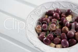 Marinated olives with herbs in a bowl on table