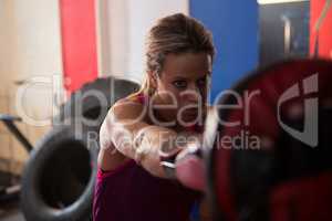 Young female boxer punching mitts