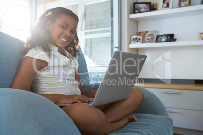 Portrait of girl with laptop sitting on armchair