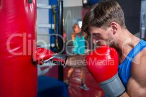 Side view of young male boxer punching red bag