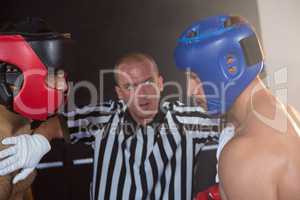 Referee stopping aggressive male boxers