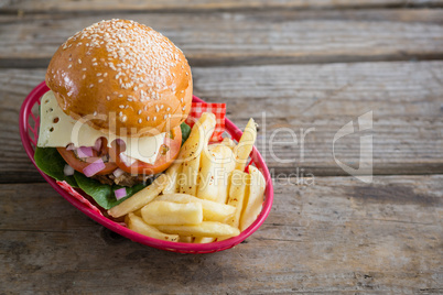 Cheeseburger and French fries in red basket
