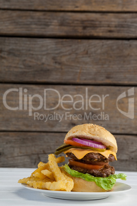 Hamburger and french fries in plate on wooden table