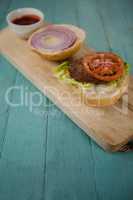 Close-up of hamburger and sauce on chopping board