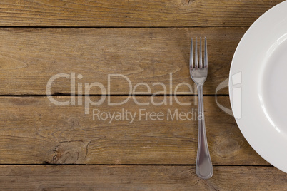 White plate and fork on wooden table