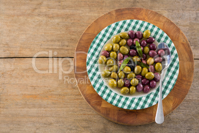 Marinated olives with herbs on wooden board