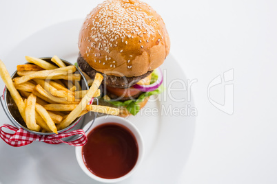 Close up of burger by french fries in container with tomato sauce