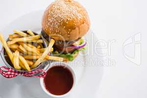 Close up of burger by french fries in container with tomato sauce