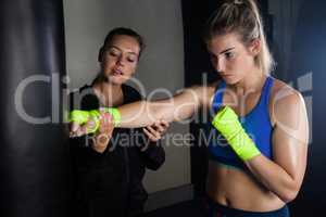 Trainer assisting woman in boxing