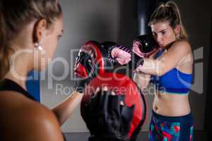 Trainer assisting woman in boxing