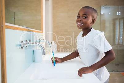 Portrait of smiling boy standing by sink with toothbrush