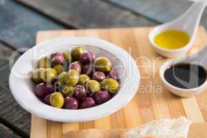 Marinated olives with olive oil on chopping board