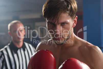 Referee looking at young male boxer