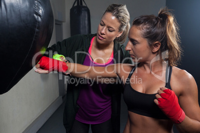 Trainer assisting woman in boxing