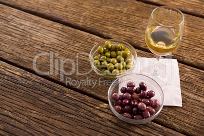 Close-up of marinated olives with glass of wine