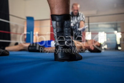 Low section of male boxer standing against referee by athlete