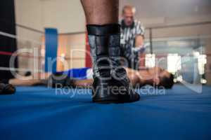 Low section of male boxer standing against referee by athlete