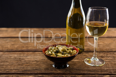 Close-up of marinated olives with glass of wine