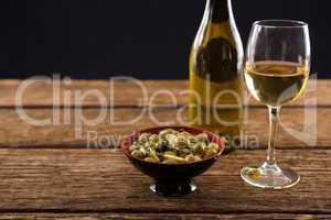 Close-up of marinated olives with glass of wine