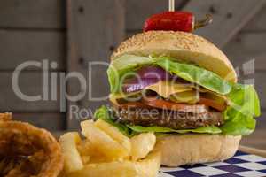 Hamburger, onion ring and french fries on chopping board