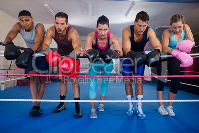 Exhausted young boxers leaning on rope