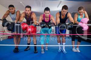 Exhausted young boxers leaning on rope